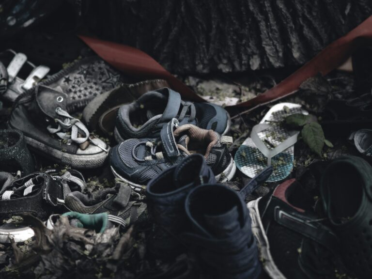 A pair of worn shoes left behind on dusty ground, symbolizing lives lost during war — a quiet tribute to memory, absence, and the human toll of conflict.