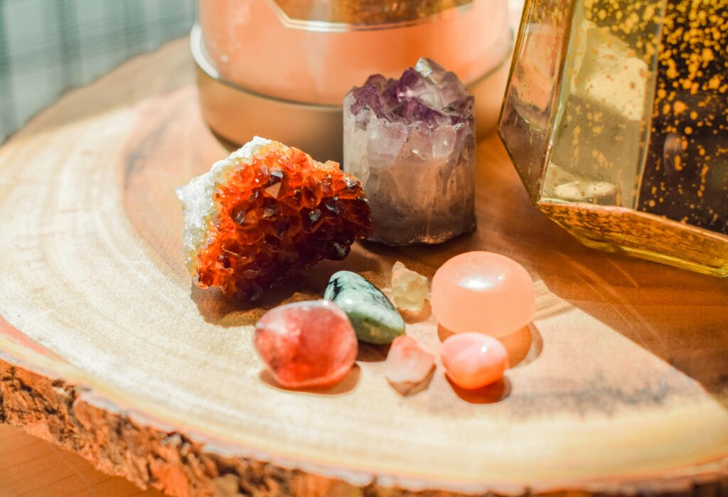 A collection of healing crystals arranged on a natural surface, including amethyst, rose quartz, and clear quartz — symbolizing energy balance, emotional healing, and holistic wellness.